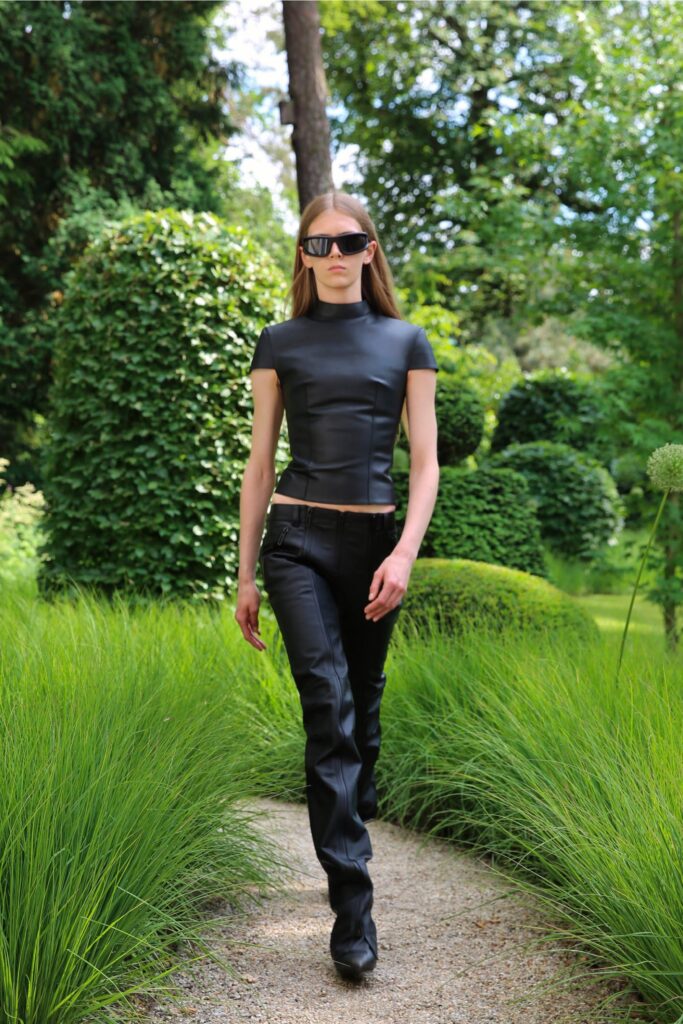 A fitted black leather top with a high neckline paired with straight-leg pants.