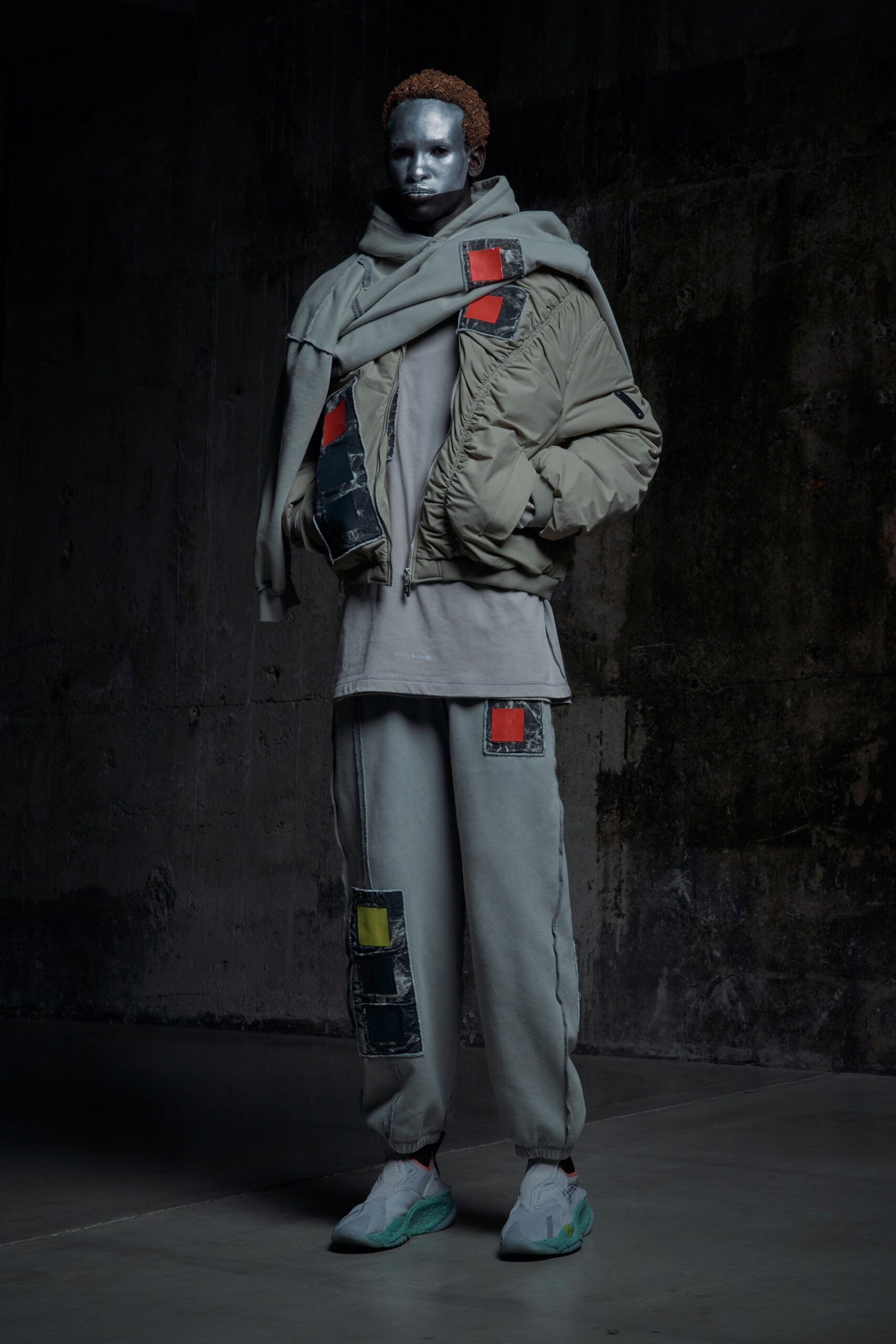 A relaxed gray jacket layered over a shirt, paired with patchwork gray pants.