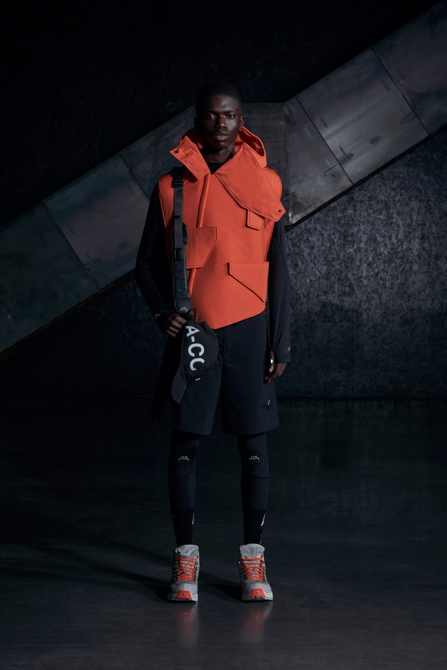 A relaxed orange cotton sleeveless vest paired with black shorts featuring an asymmetric design.