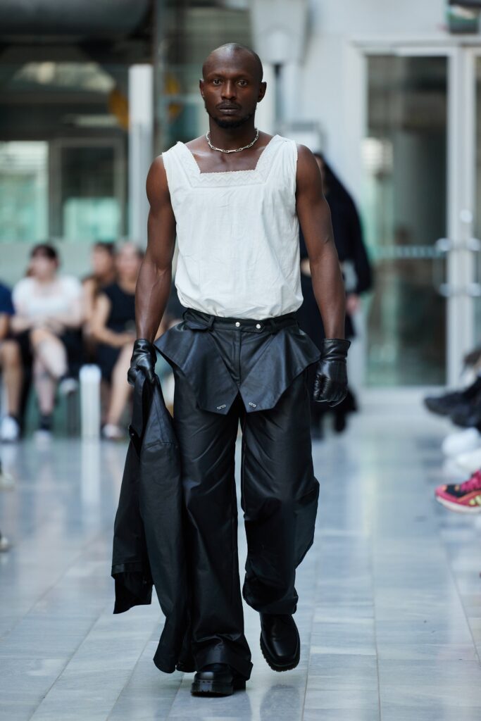 A fitted white sleeveless top paired with black leather pants, showcasing a modern streetwear aesthetic.