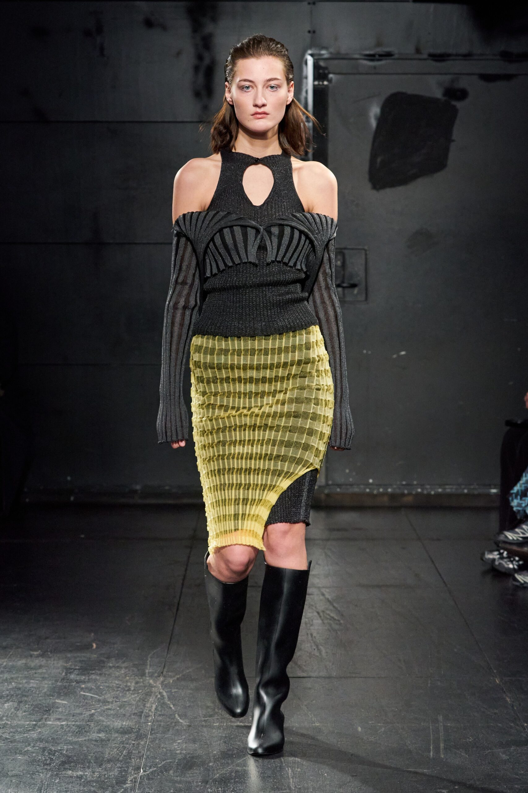 A fitted dress featuring a black knit top with cutouts and an asymmetric yellow skirt.