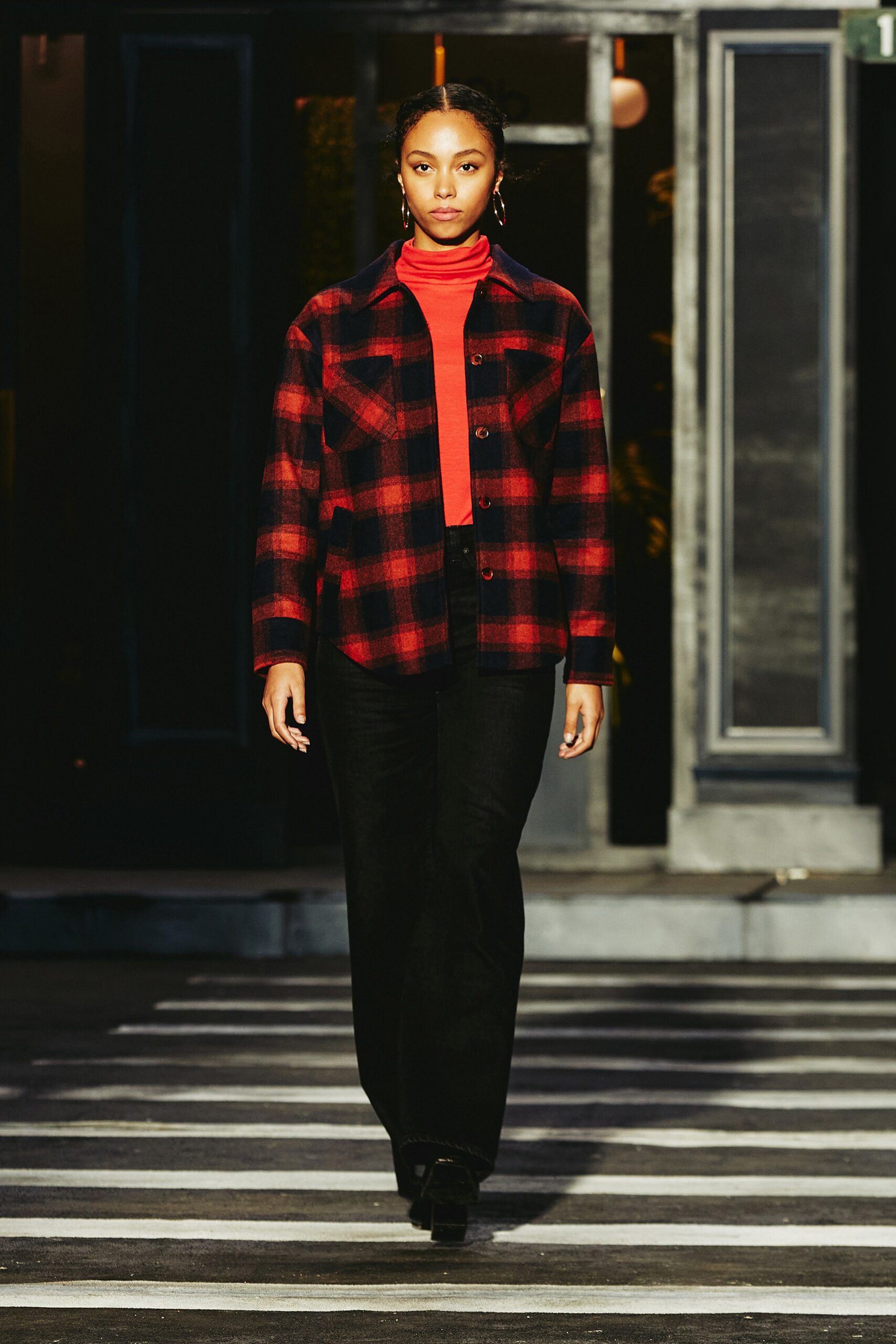 A fitted red and black checked shirt paired with black pants, featuring a long-sleeve design.