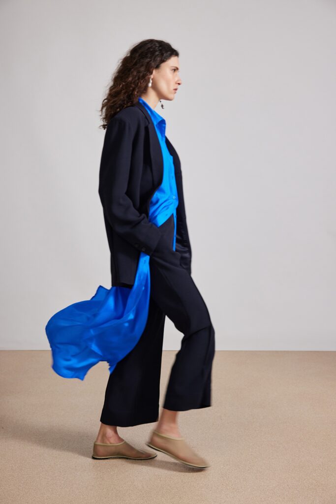 A relaxed black jacket paired with blue silk pants, featuring a long-sleeve and collared design.