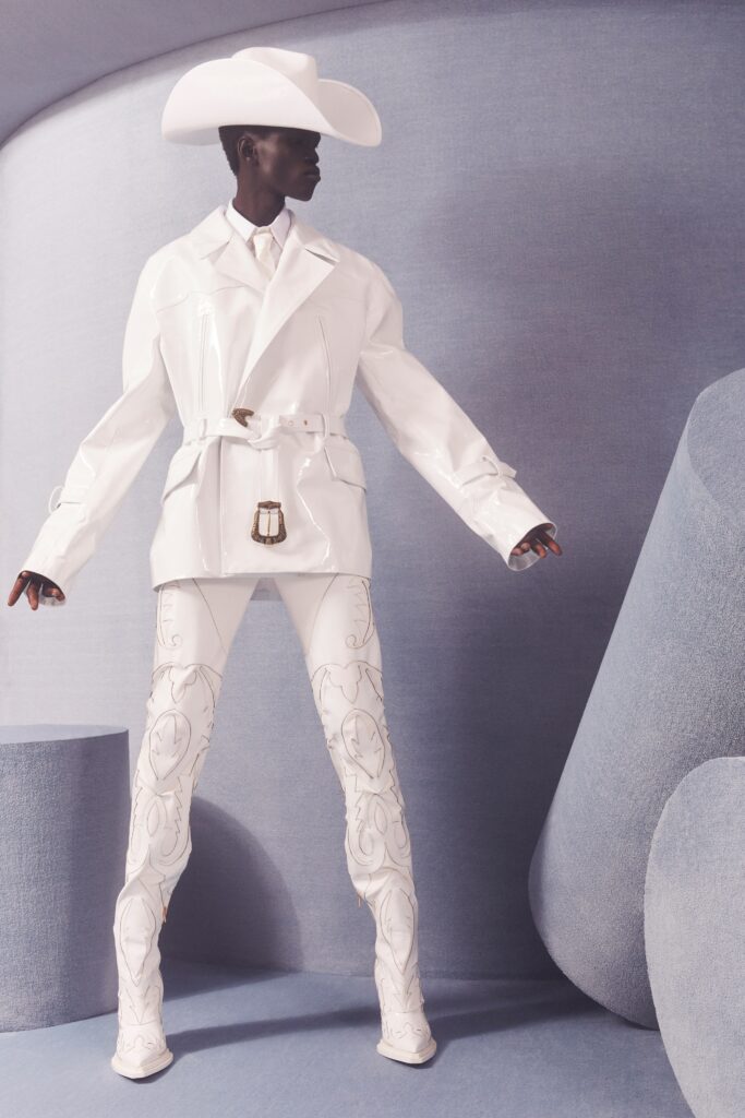 A fitted white leather jacket paired with tailored white pants featuring intricate designs.