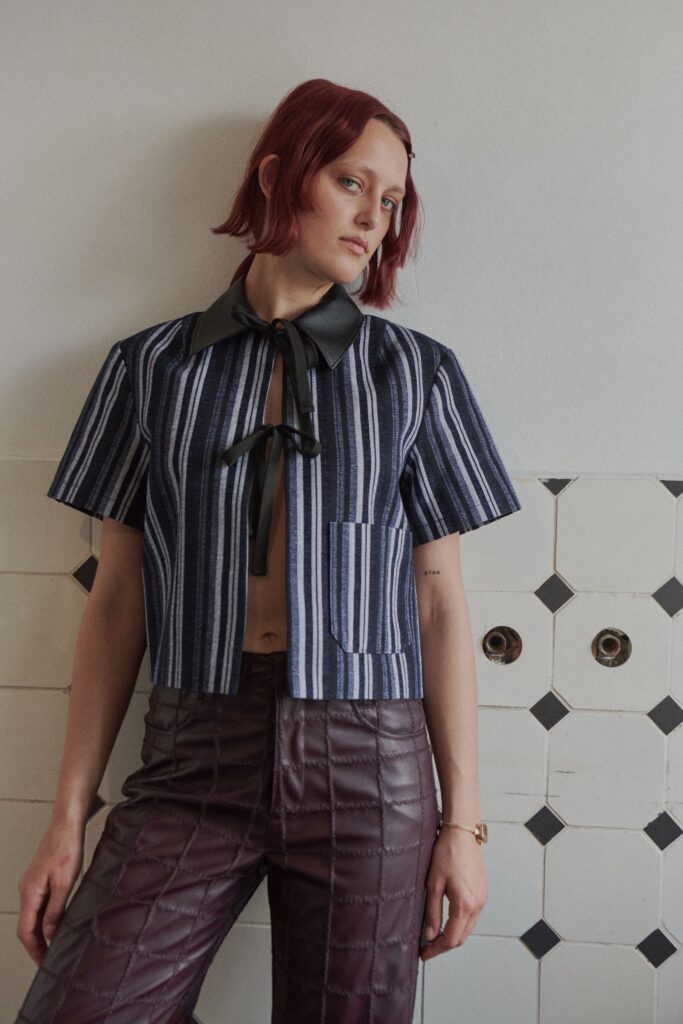 A fitted striped blue cotton top with a collared neckline paired with brown quilted pants.