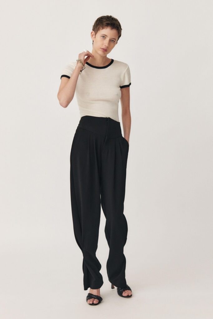 A fitted white short-sleeve top paired with high-waisted black pleated pants.