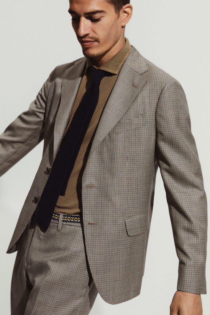 A tailored beige suit with a checked pattern and long sleeves, featuring a collared shirt.