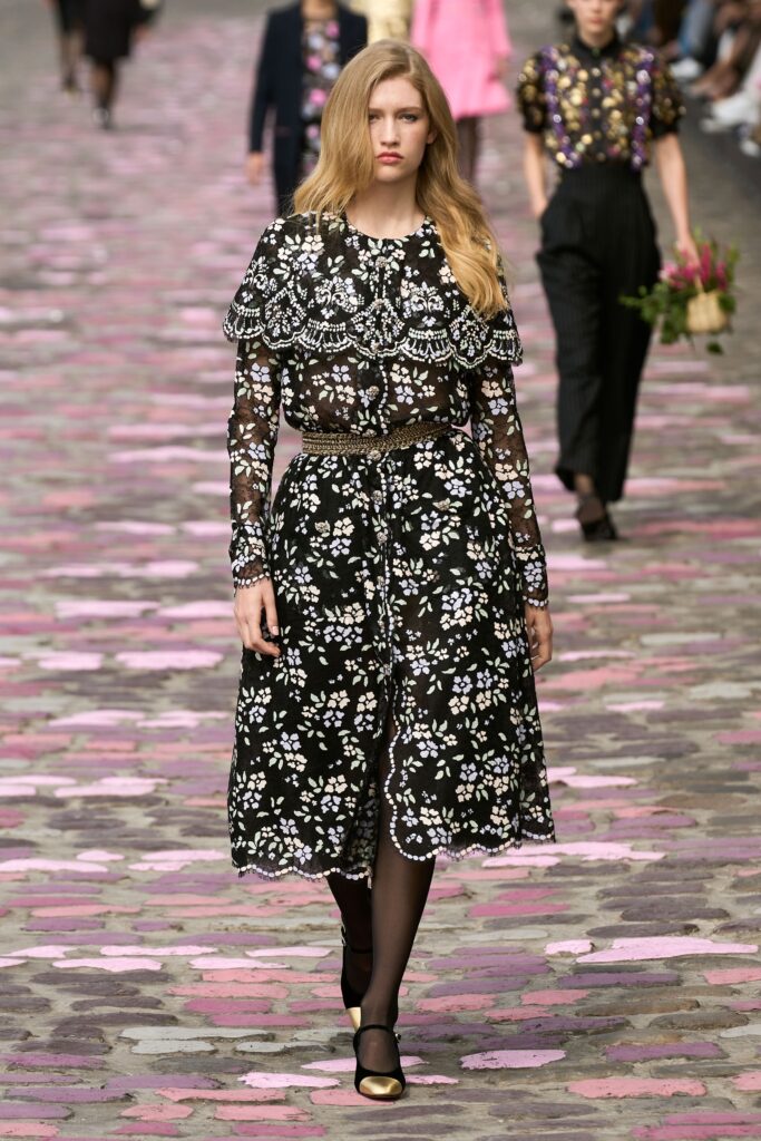 A fitted black lace dress with long sleeves, a collared neckline, and floral detailing.