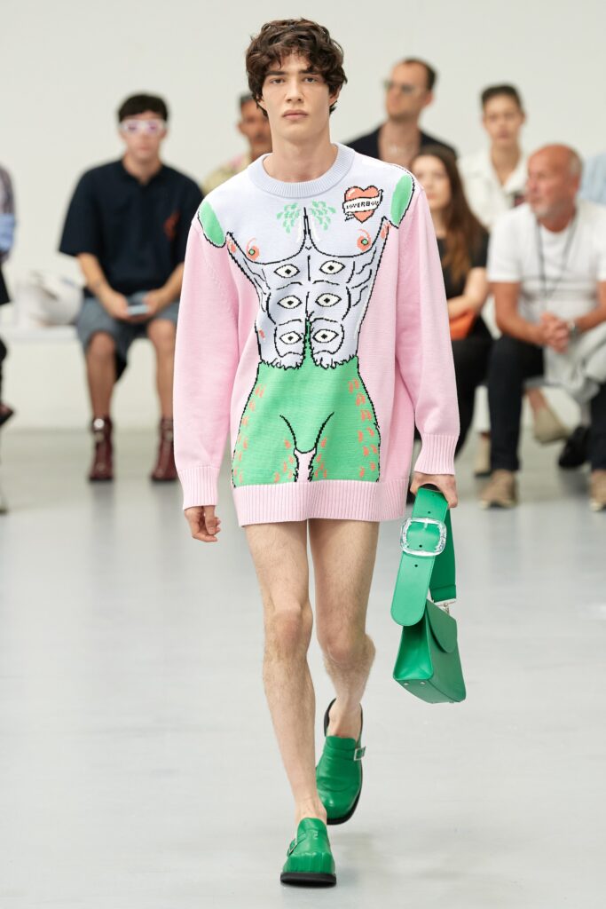 A fitted pink sweater dress with long sleeves and a printed design featuring green accents.