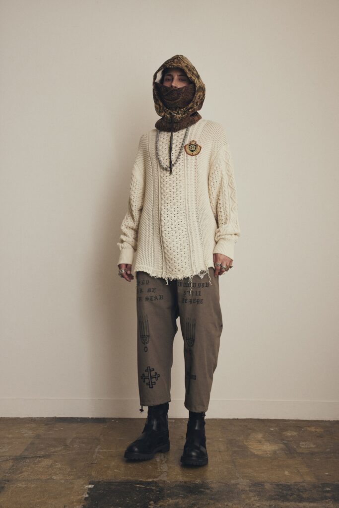 A relaxed beige sweater with long sleeves paired with brown pants, creating a layered look.