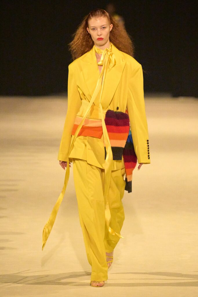 A tailored yellow suit with long sleeves, a collared shirt, and an asymmetric design detail.