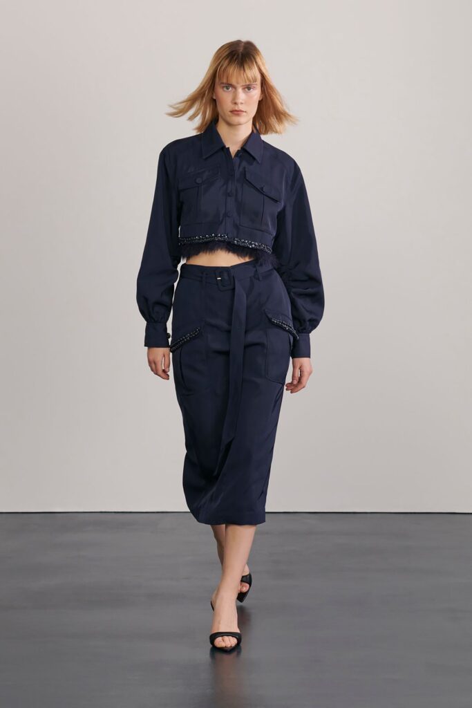 A fitted navy cotton top with long sleeves and a collared design paired with an asymmetric skirt.