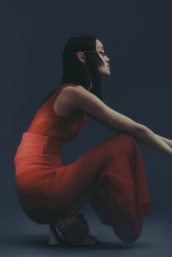 A fitted red knit dress with a sleeveless design and flared silhouette.