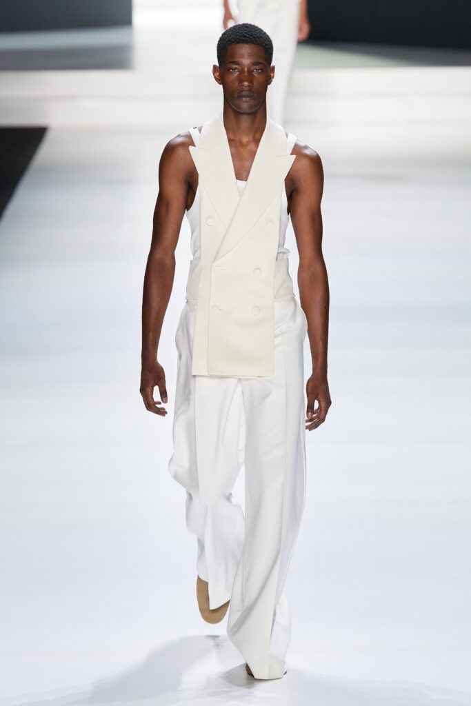 A fitted white sleeveless suit with a collared design and asymmetric details.
