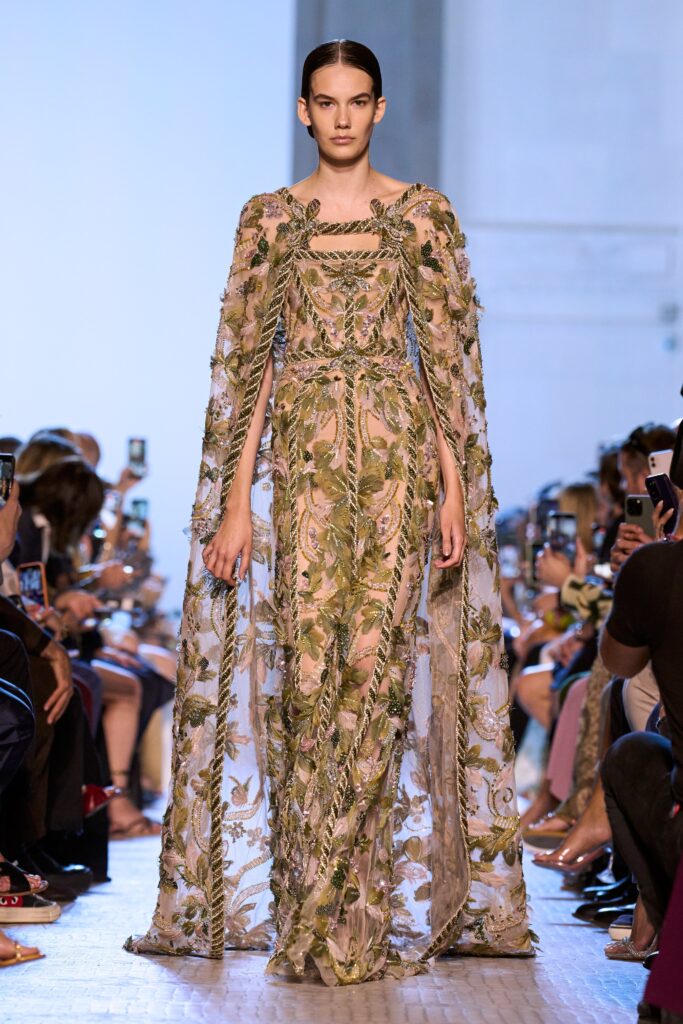 A fitted green silk dress with a V-neckline, long sleeves, and embroidered tiered details.