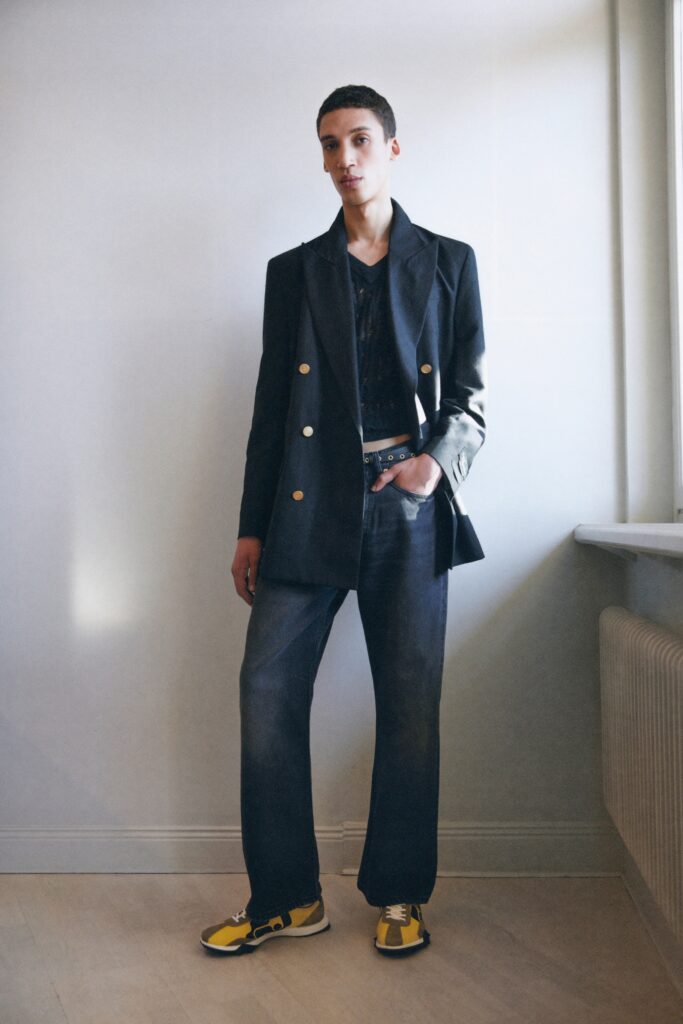 A relaxed black jacket with a collared design paired with wide-leg blue pants.