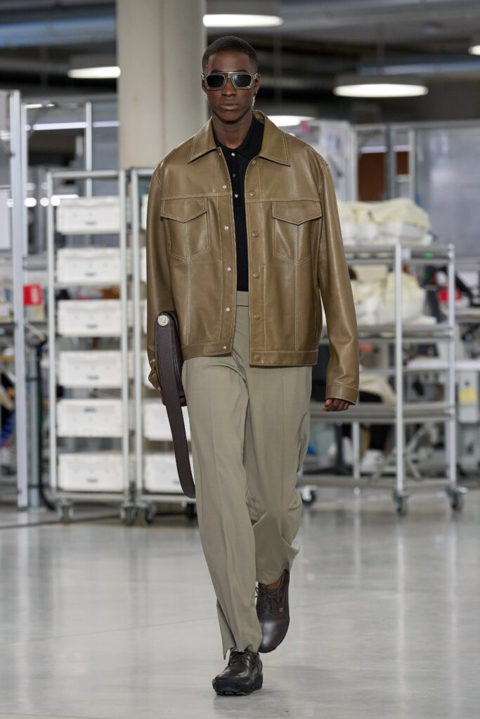 A relaxed brown leather jacket with a collared neckline paired with beige cotton pants.