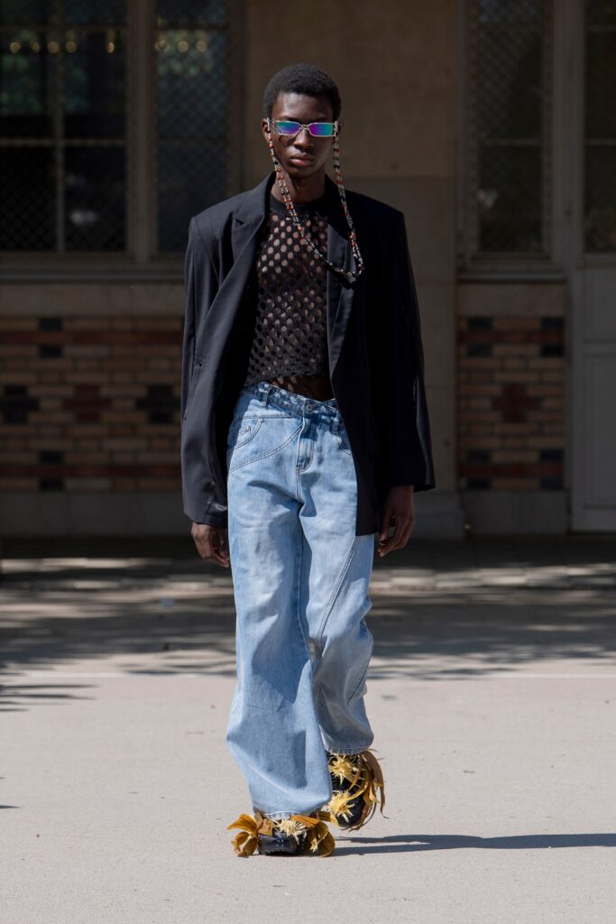 A relaxed black jacket paired with wide-leg blue denim pants for a stylish look.