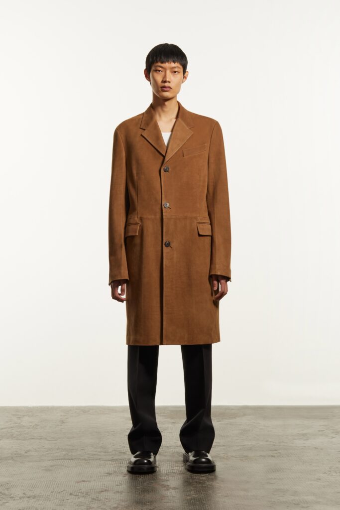 A relaxed brown cotton coat with a collared neckline, paired with black pants.