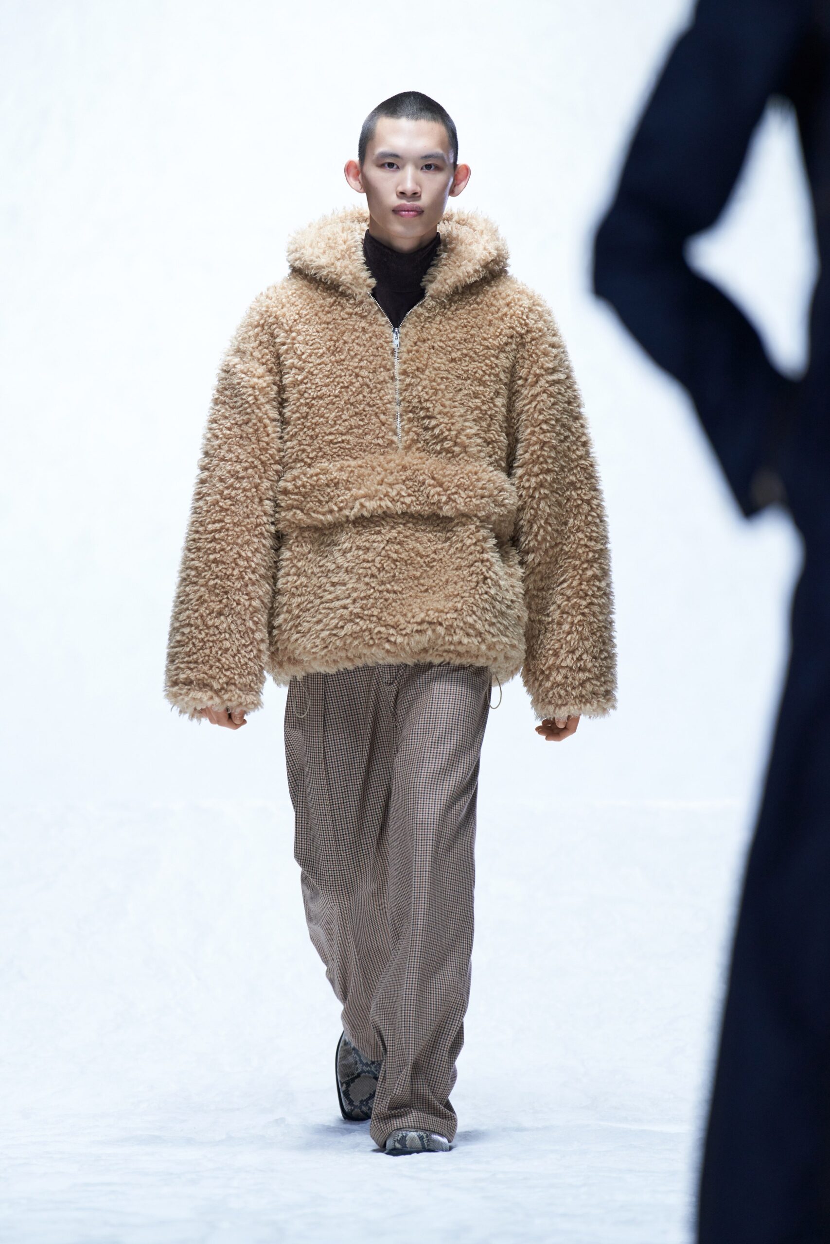 A relaxed brown faux-fur jacket with a hood paired with stylish cotton pants.