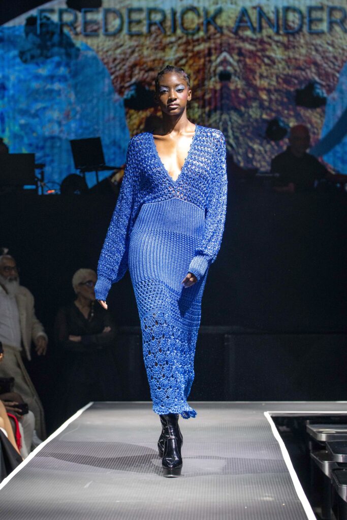 A fitted blue knit dress with a V-neckline and long sleeves featuring an asymmetric design.