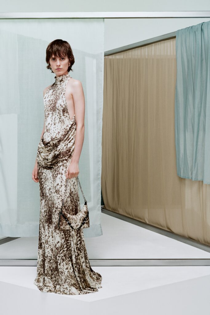 A fitted silk dress with a high-neck and draped design in beige and brown tones.