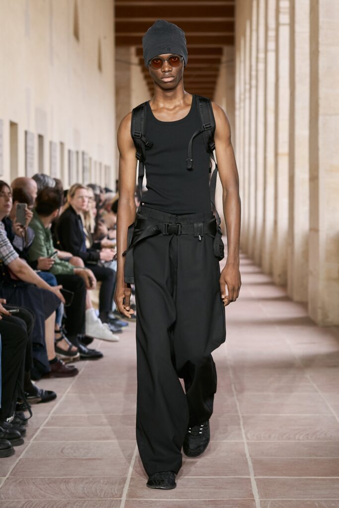 A relaxed black tank-top paired with high-waisted wide-leg pants, creating a modern silhouette.