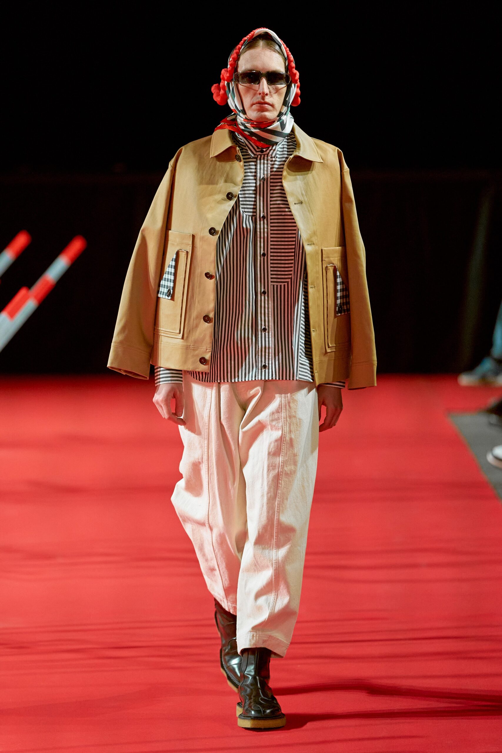 A relaxed beige jacket layered over a long-sleeve striped shirt, paired with white pants.