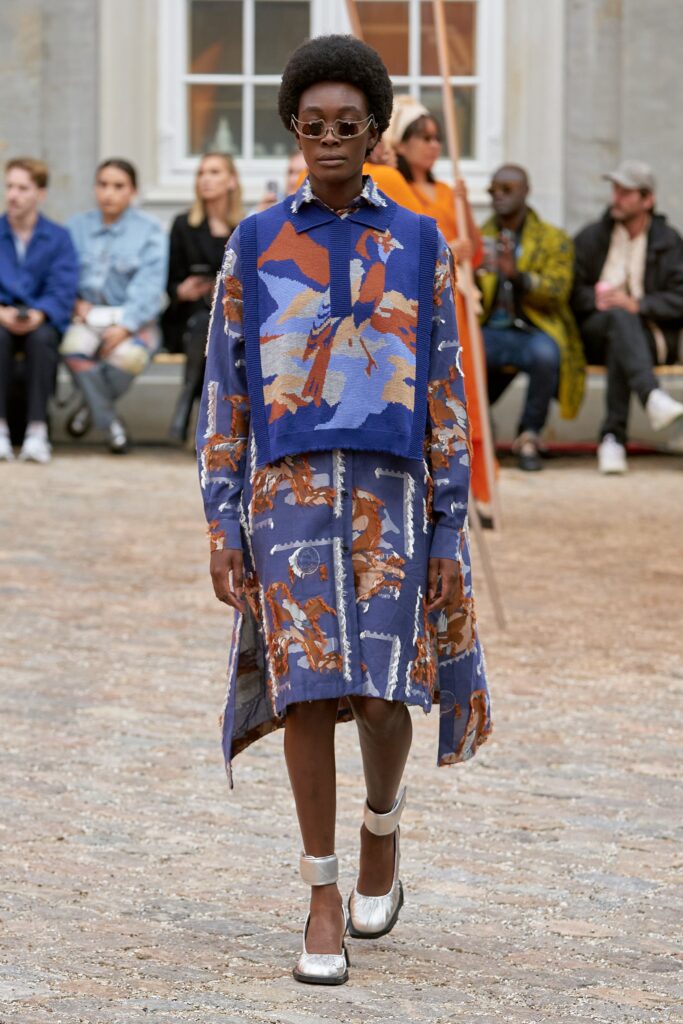 A relaxed blue printed dress with long sleeves and a collared neckline featuring an asymmetric design.