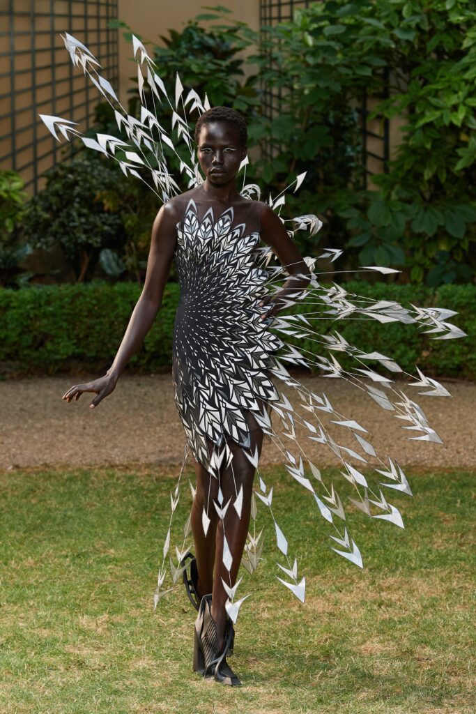 A fitted black and white sleeveless dress with a V-neckline and asymmetric design.