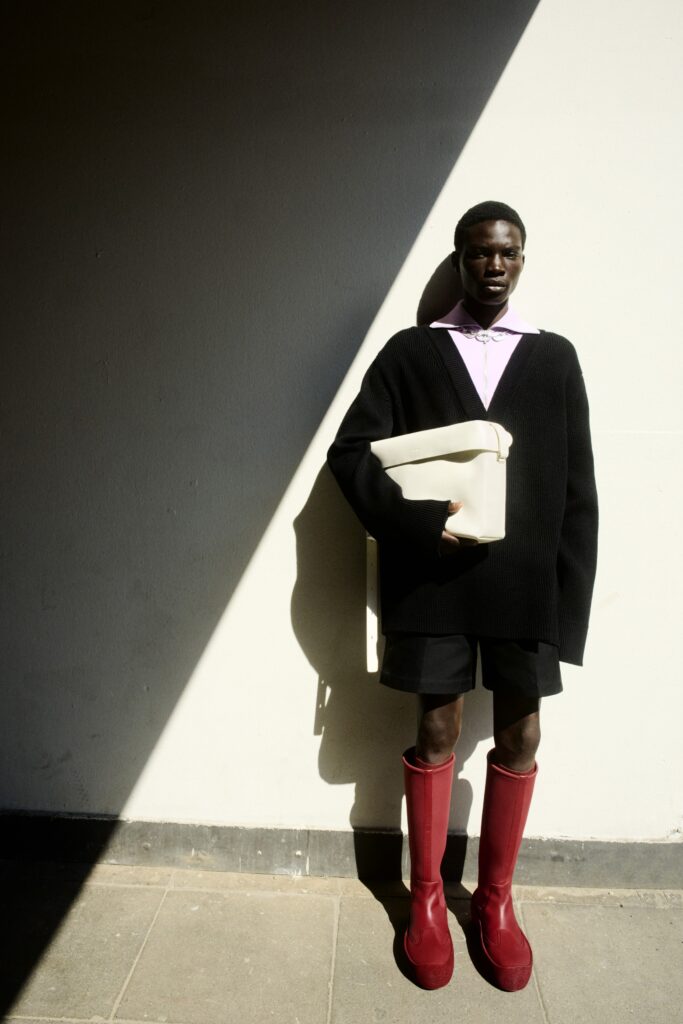 An oversized black cotton sweater paired with red knee-high boots and shorts.