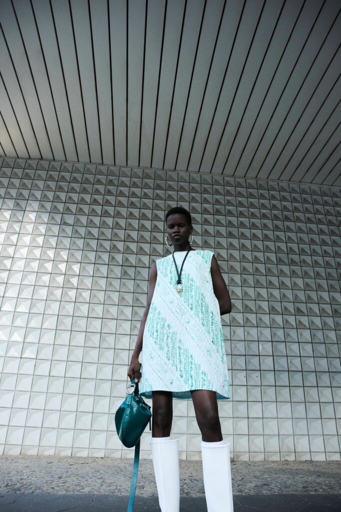 A fitted sleeveless dress with an asymmetric design in white and green colors.