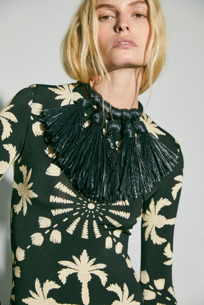A fitted black and beige printed dress with long sleeves and a high neckline.