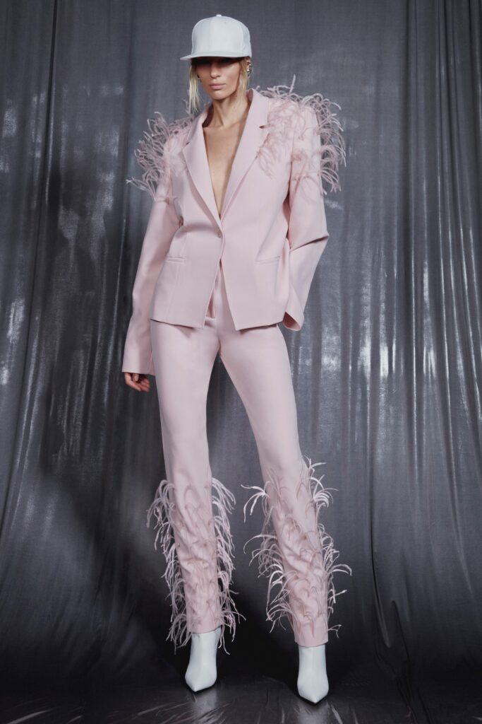 A fitted pink suit featuring fringed details and a V-neckline for a bold runway look.