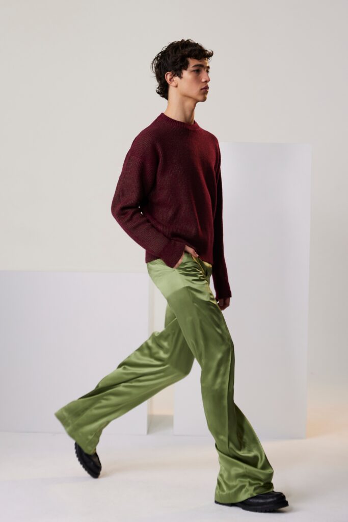 A relaxed burgundy cotton sweater paired with wide-leg green silk pants.