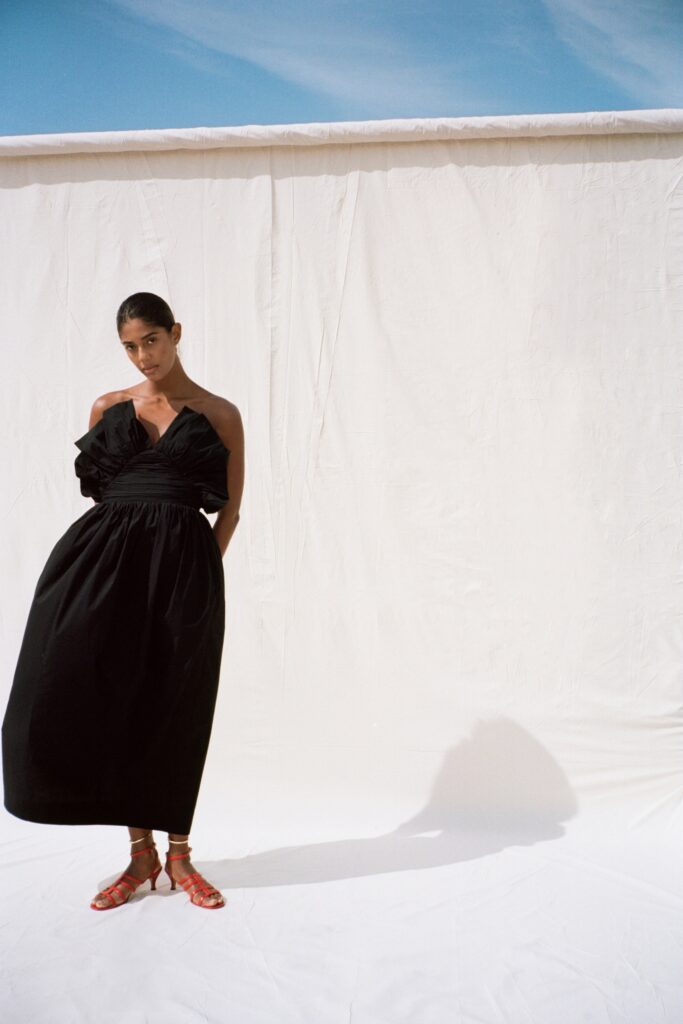 A relaxed black sleeveless dress with a V-neckline and tiered design.