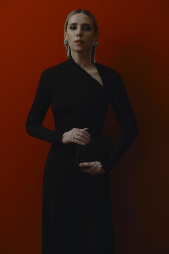A fitted black silk dress with long sleeves and an asymmetric design.