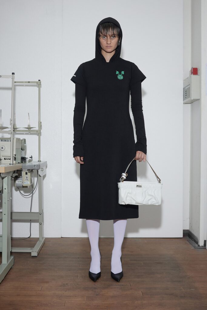A fitted black dress with short sleeves and a hood, featuring a straight-leg silhouette.