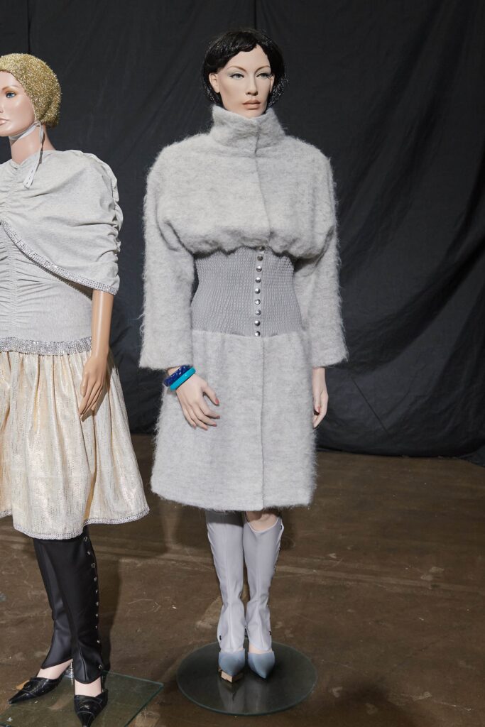 A relaxed gray wool coat with long sleeves and a high neckline, featuring button details.