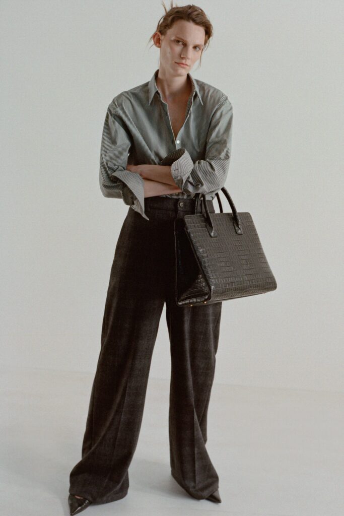 A relaxed long-sleeve collared striped shirt paired with wide-leg black pants.