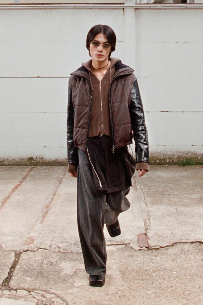 A relaxed brown jacket paired with wide-leg black pants, featuring a layered look.