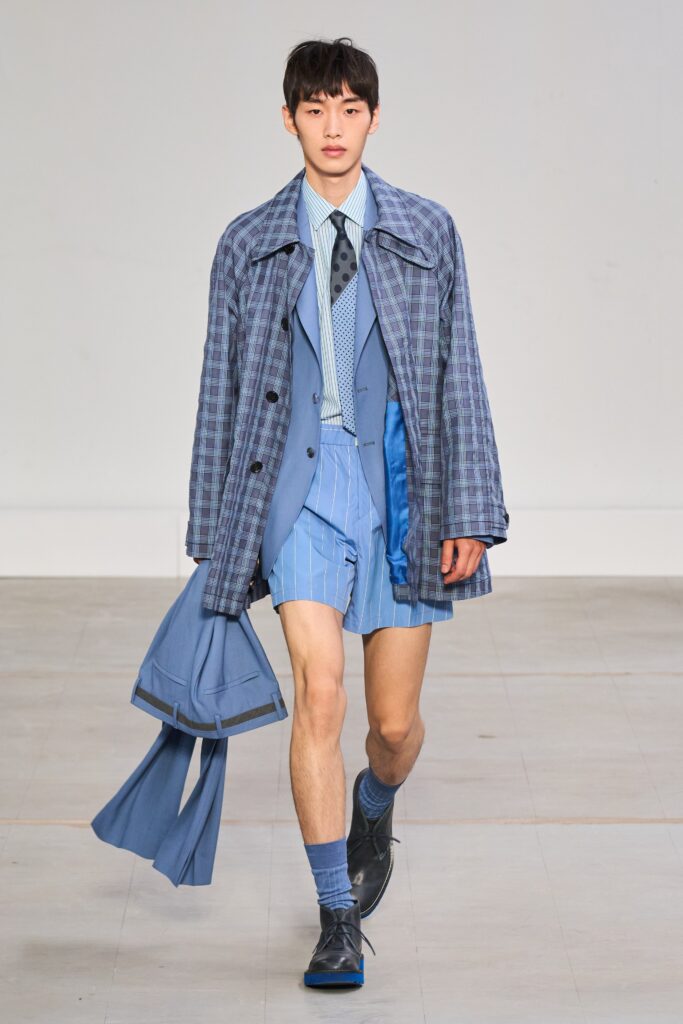 A fitted blue cotton jacket with long sleeves and collared design, paired with striped shorts.