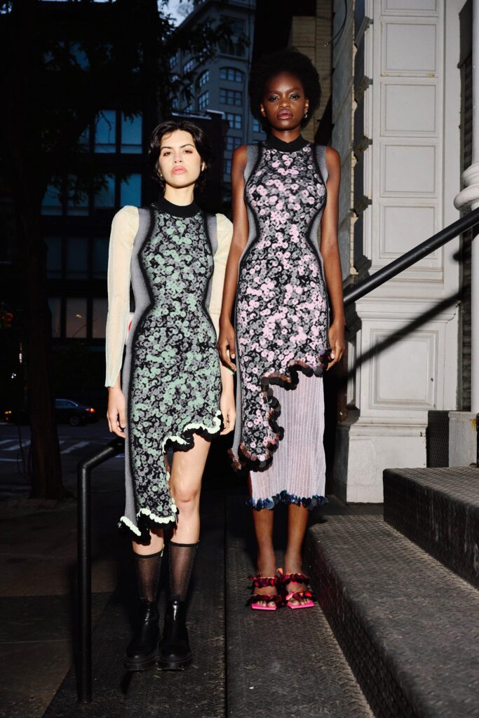 A fitted dress with an asymmetric hemline, featuring floral patterns in black, green, and pink.