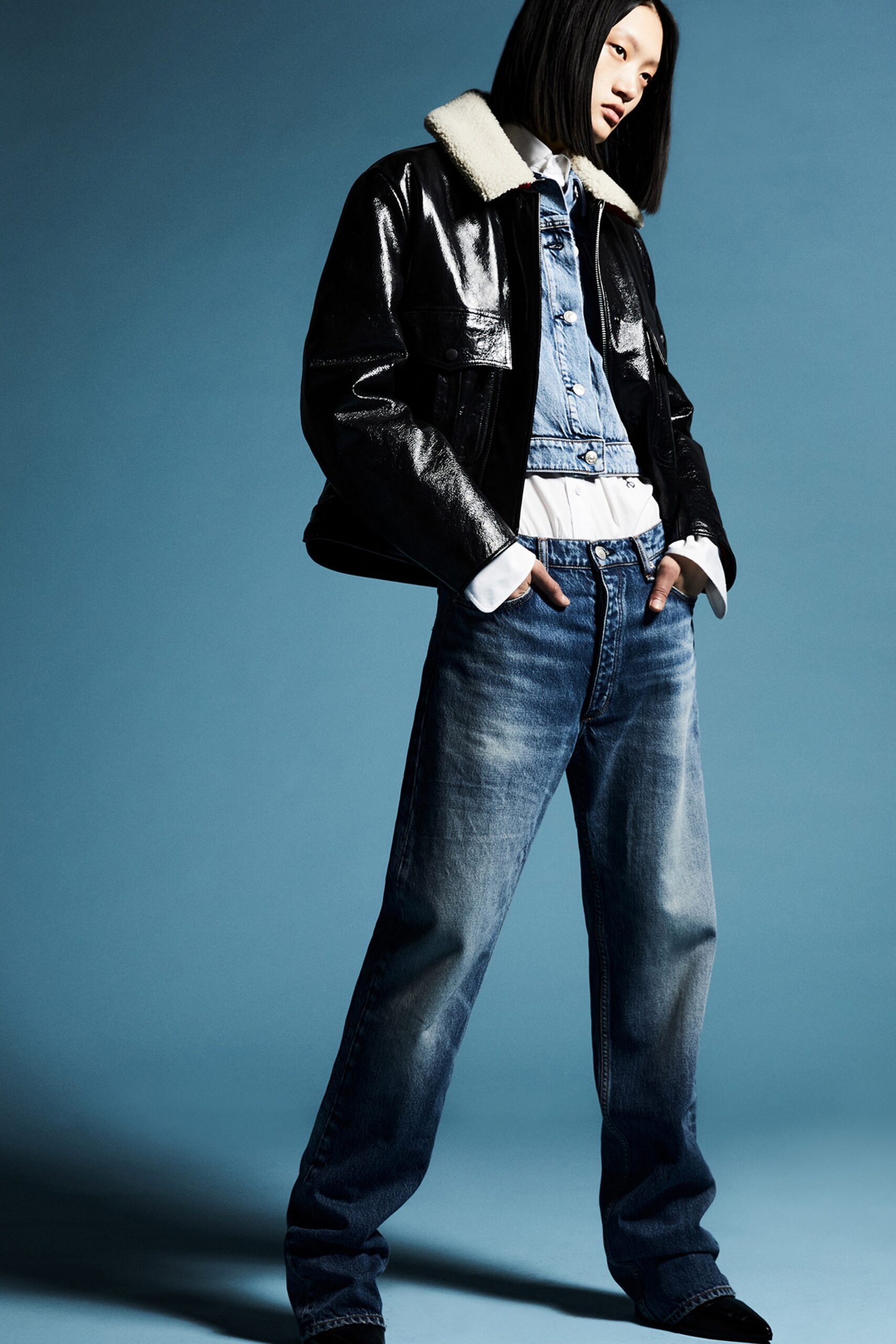 A relaxed black leather jacket paired with blue denim jeans featuring a collared design.