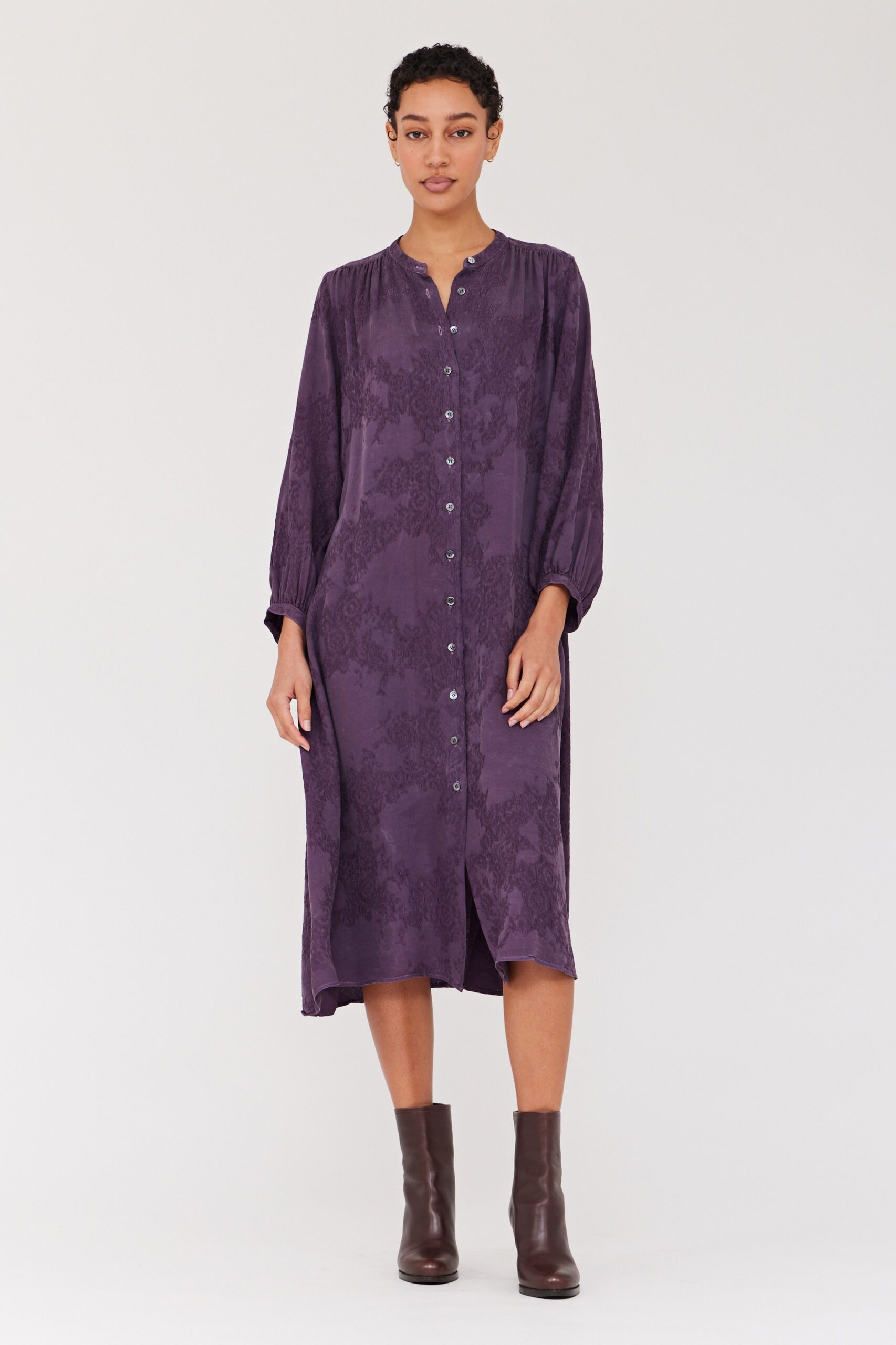 A relaxed purple silk dress with long sleeves and a collared neckline, featuring button details.