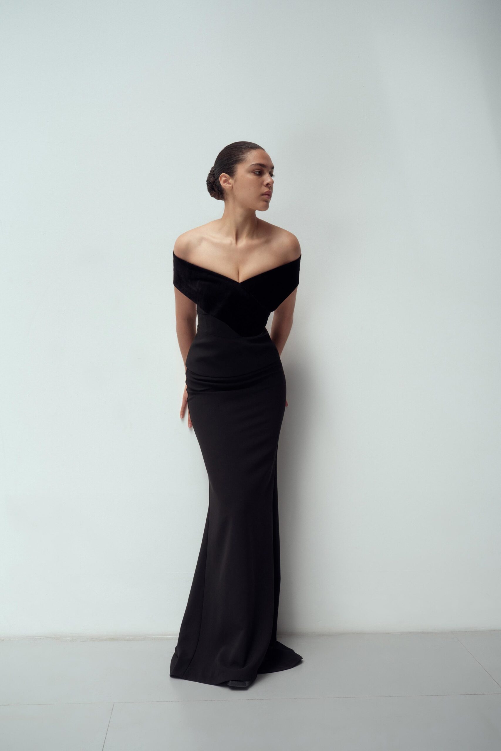 A fitted black velvet gown with a V-neckline and sleek silhouette.