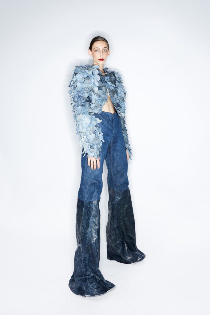 A fitted blue denim jacket with layered details paired with fitted denim pants.