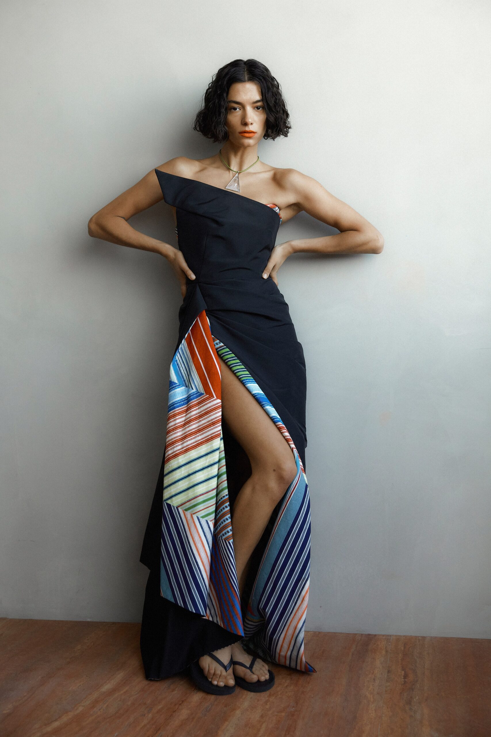 A fitted black dress with multicolor asymmetric details and a thigh-high slit.