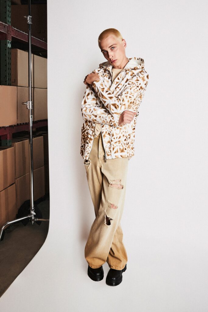 A relaxed-fit printed beige jacket paired with distressed beige pants for a casual look.