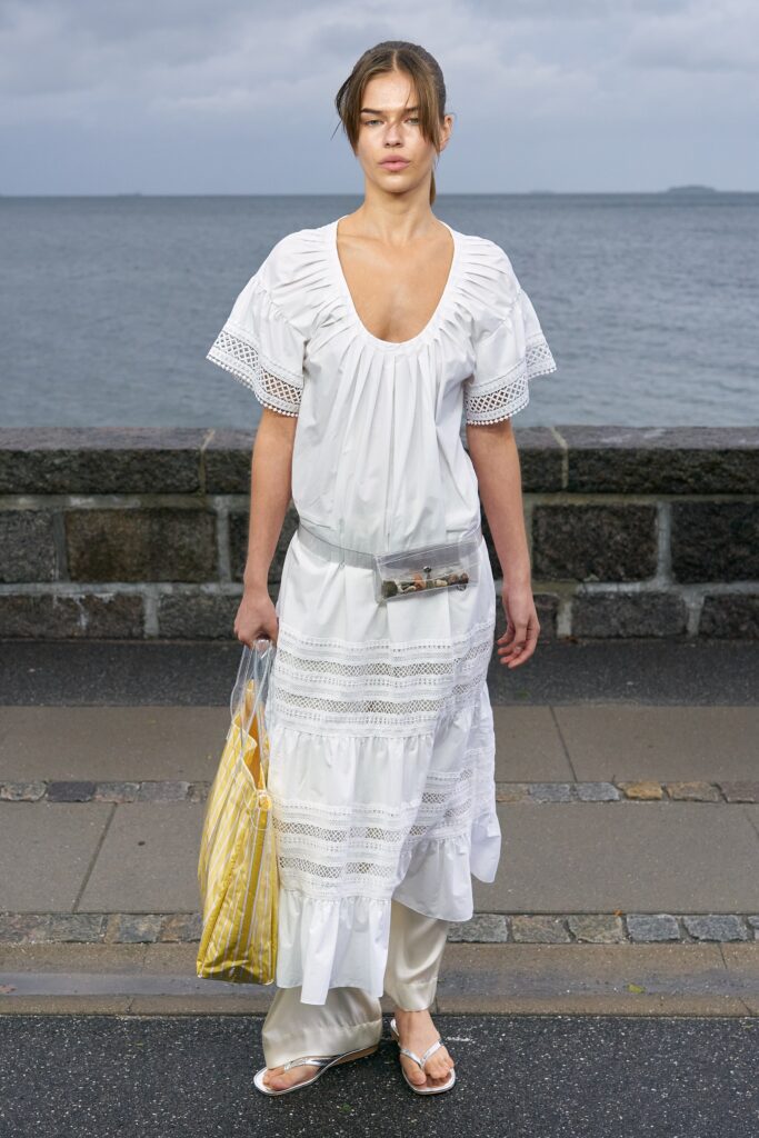 A relaxed white cotton dress with short sleeves, a V-neckline, and tiered design.